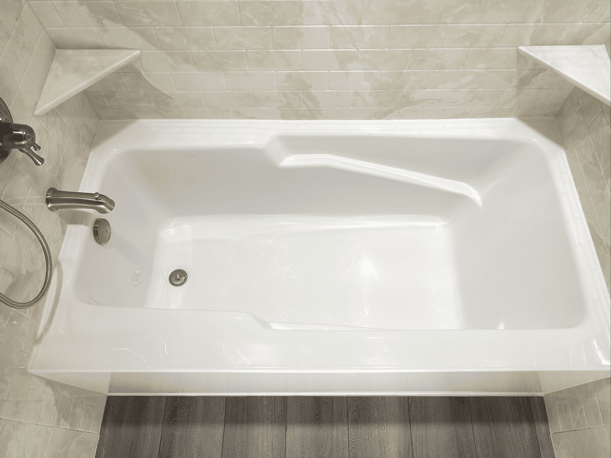 Bathtub with tiled surround and corner shelving
