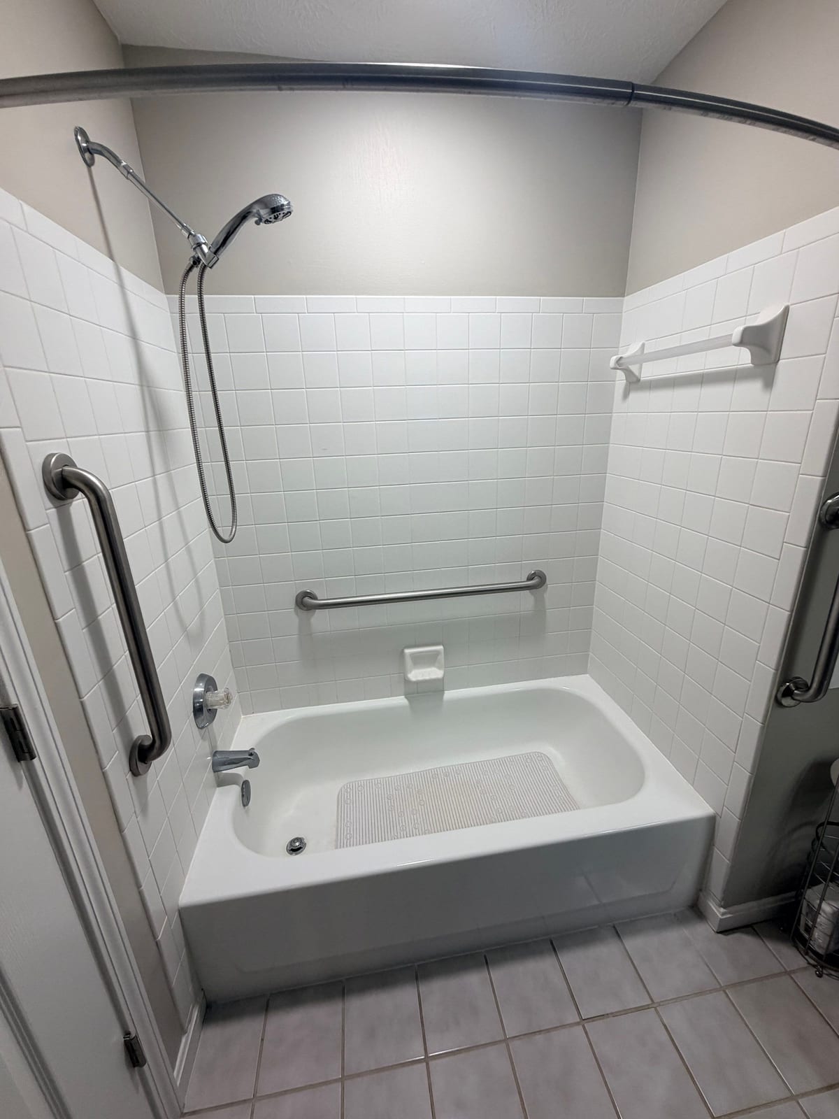 Dated white tile tub surround with grab bars, before replacement by SAS Home Solutions
