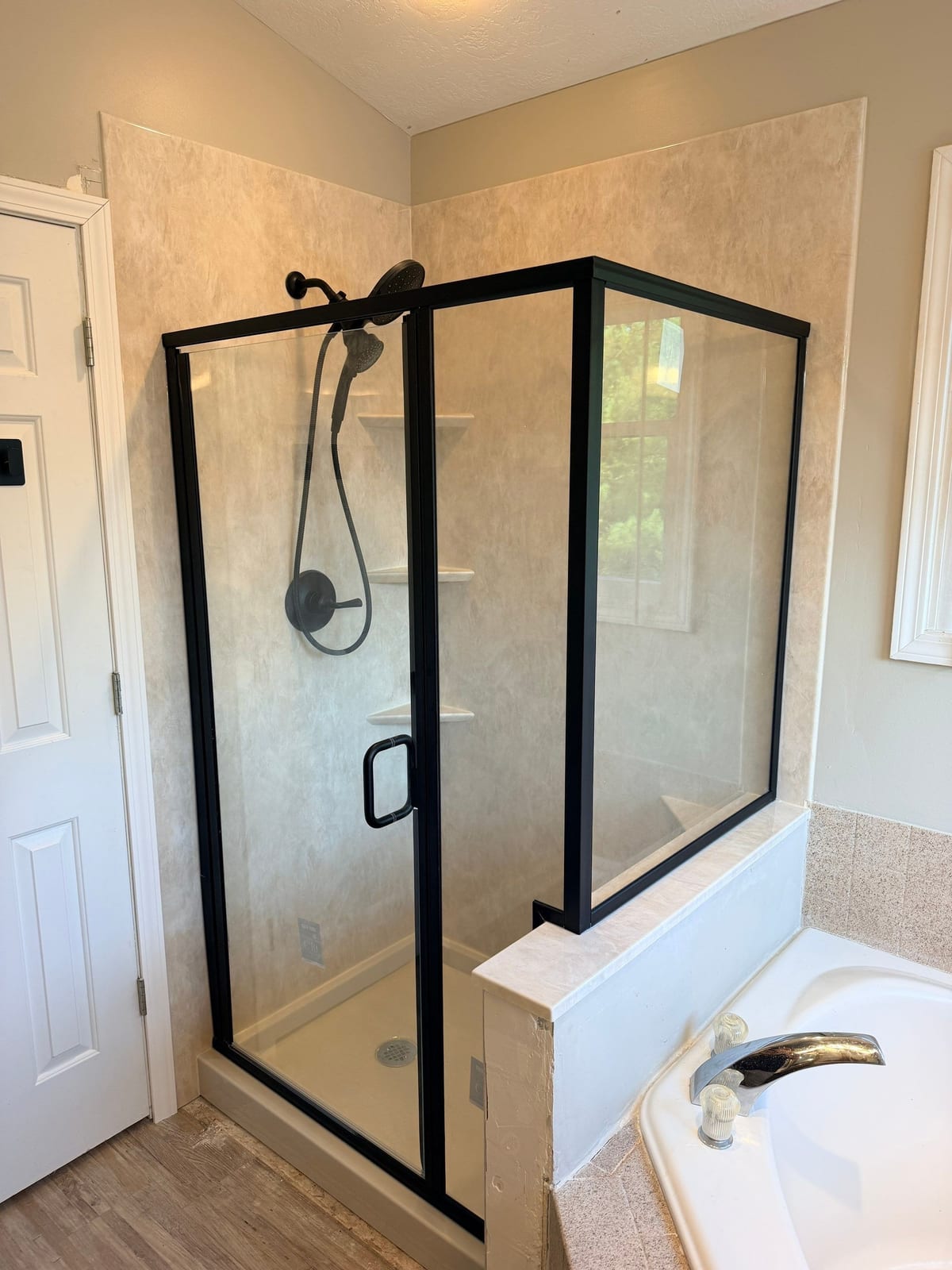 The same corner after a wider walk-in shower with a framed glass enclosure was installed by SAS Home Solutions